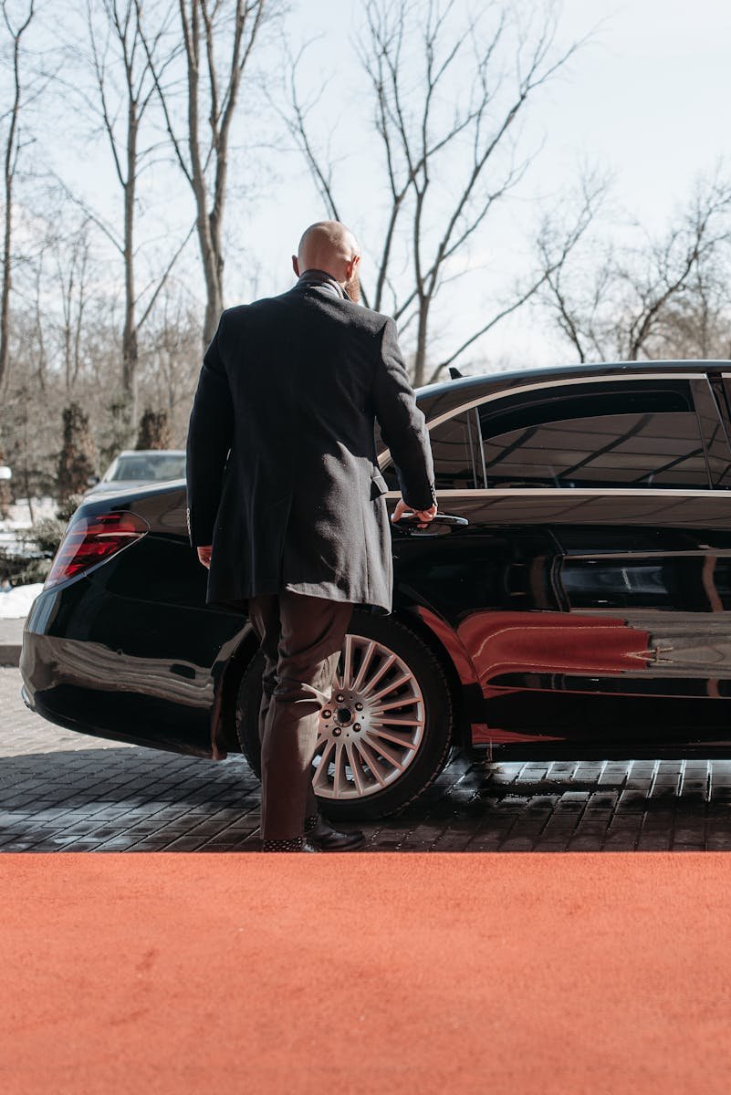 Car Service Palm Beach Gardens FL: professional chauffeur waiting next to a luxury black car on PGA Boulevard.